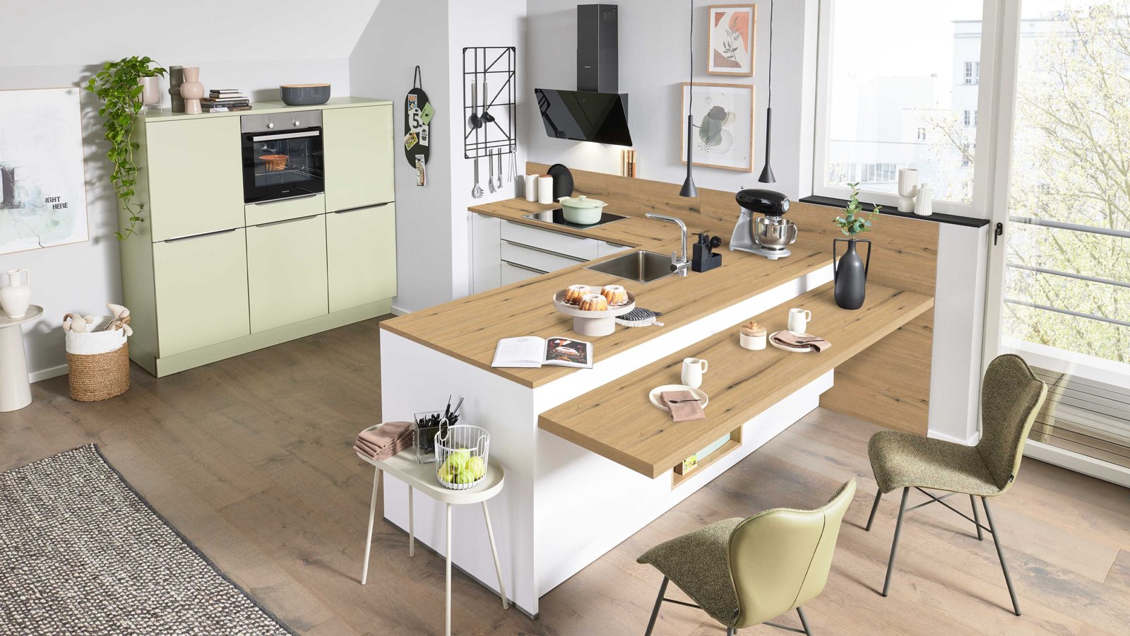 Interliving Interliving Küche Serie 3109 – Offene Küche in sanftem Grün mit Holzarbeitsplatte und gemütlichem integriertem Essbereich