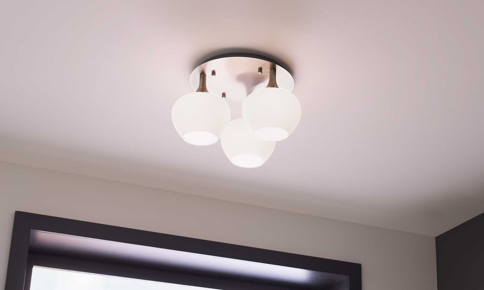 Interliving Deckenlampe mit drei kugelförmigen Mattglasschirmen und nickelfarbenem Baldachin